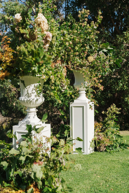 A styled garden ceremony arbour with lush seasonal florals