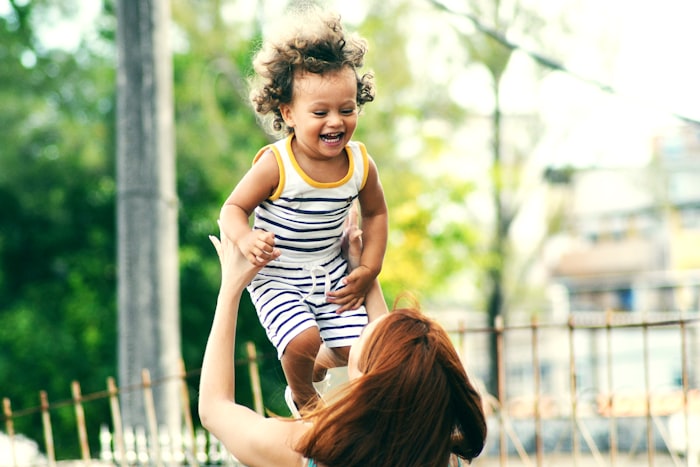 Mother lifting laughing toddler in the air